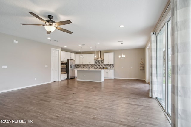 300 Downs Corner Rd, Saint Augustine, FL 32092 - unfurnished living room featuring baseboards, ceiling fan with notable chandelier, wood finished floors, and a wealth of natural light