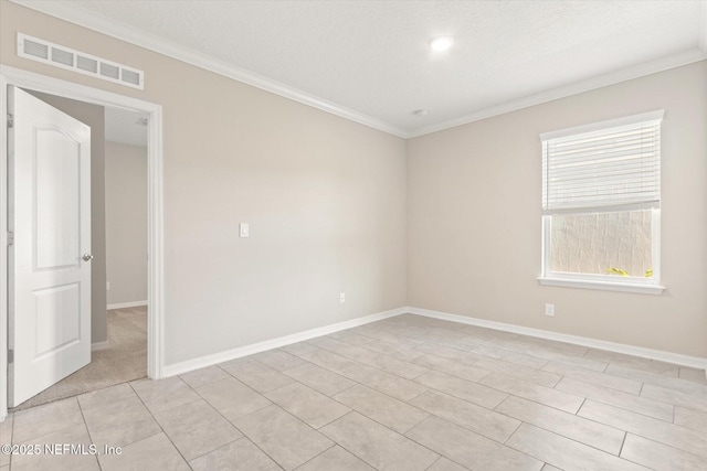 empty room featuring baseboards, visible vents, and ornamental molding