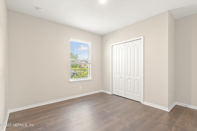 unfurnished bedroom featuring baseboards, a closet, and wood finished floors