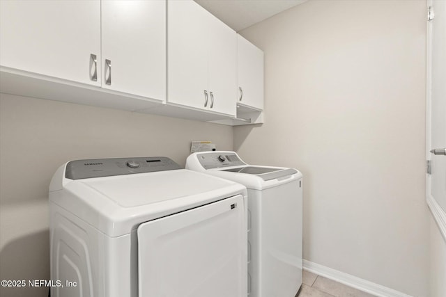 clothes washing area featuring light tile patterned floors, baseboards, cabinet space, and washer and dryer