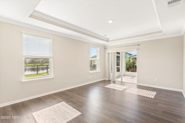 spare room featuring crown molding, a tray ceiling, dark wood-type flooring, and visible vents