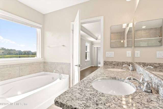 bathroom with double vanity, a sink, and a garden tub