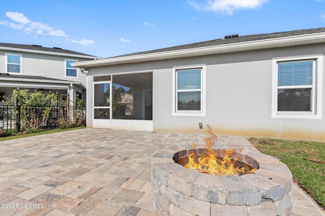 back of property with a sunroom, fence, an outdoor fire pit, a patio, and stucco siding