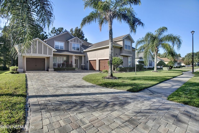 view of front facade featuring a garage, stucco siding, decorative driveway, and a front yard