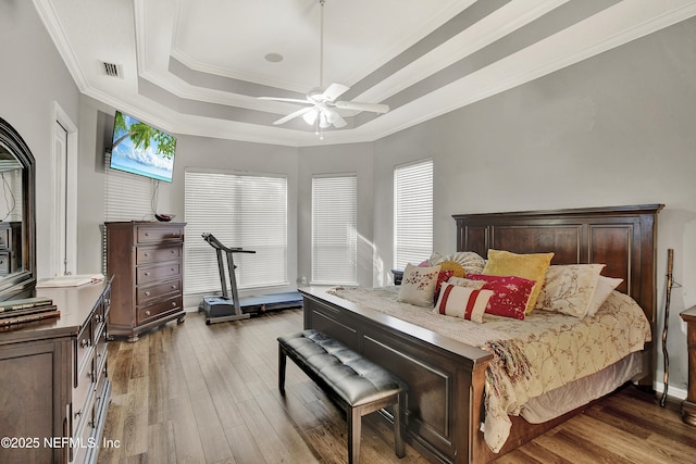 bedroom featuring visible vents, ornamental molding, wood finished floors, and a tray ceiling
