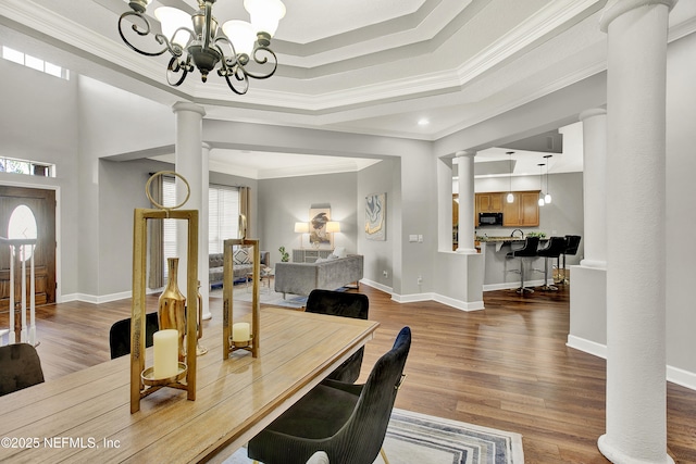 office featuring ornate columns, ornamental molding, wood finished floors, and a chandelier