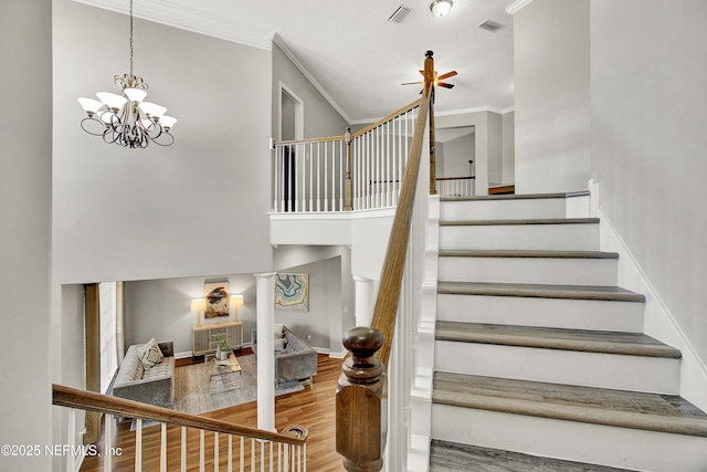 stairs with crown molding, visible vents, and wood finished floors