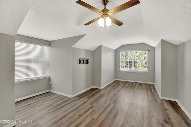 bonus room with ceiling fan, a textured ceiling, vaulted ceiling, wood finished floors, and baseboards