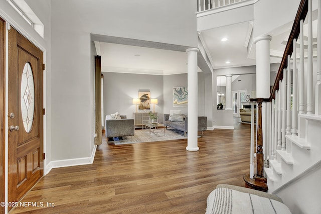 foyer entrance featuring baseboards, decorative columns, ornamental molding, and stairway