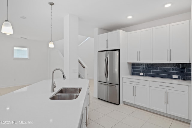 kitchen featuring freestanding refrigerator, light countertops, white cabinets, and a sink