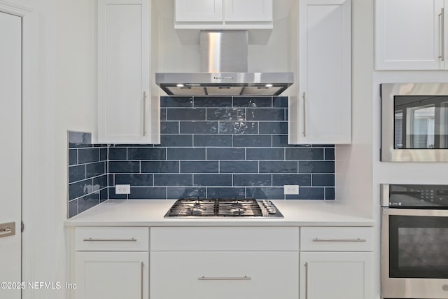 kitchen with white cabinetry, wall chimney range hood, light countertops, tasteful backsplash, and appliances with stainless steel finishes