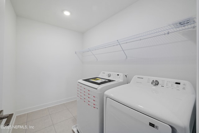 washroom with baseboards, washing machine and dryer, laundry area, and light tile patterned floors