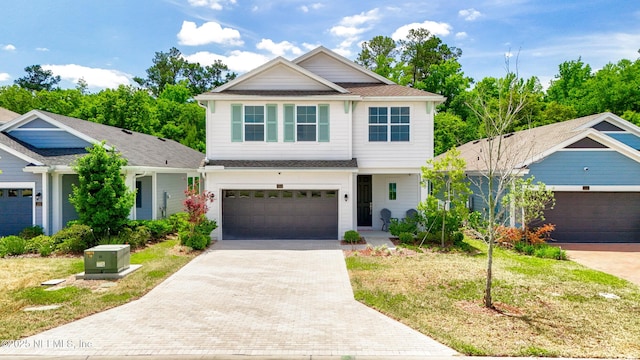 craftsman inspired home featuring an attached garage, a shingled roof, driveway, and a front lawn