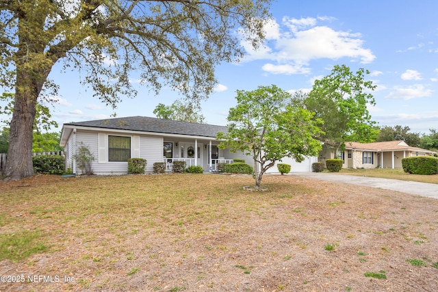 single story home featuring a porch, an attached garage, concrete driveway, and a front yard