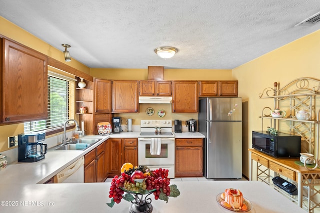 kitchen featuring visible vents, white appliances, light countertops, under cabinet range hood, and a sink