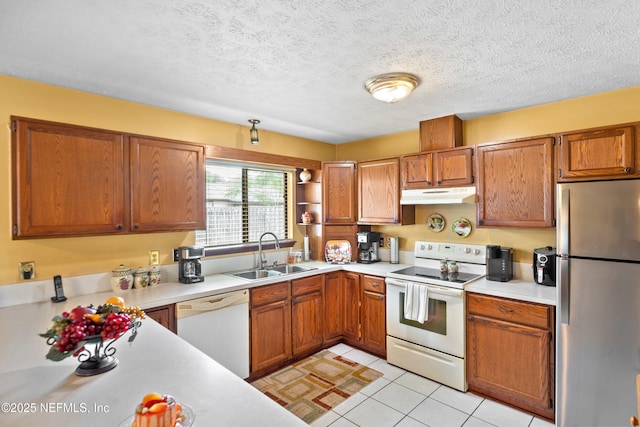 kitchen with brown cabinets, a sink, white appliances, light countertops, and under cabinet range hood