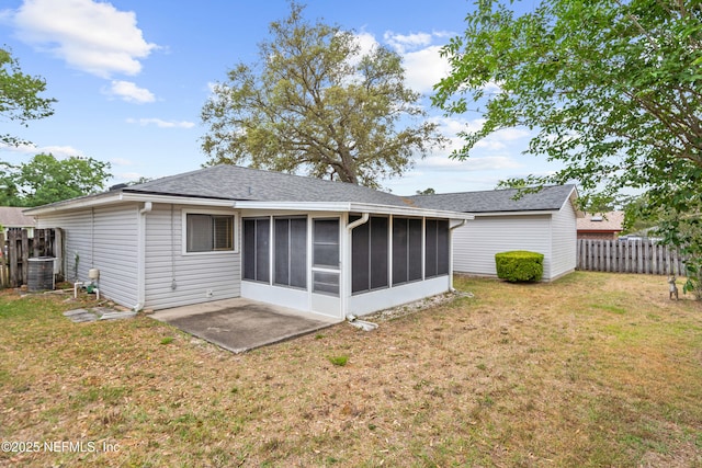rear view of house with roof with shingles, a sunroom, central AC, fence, and a yard