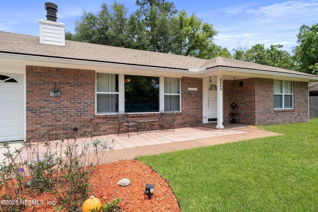 ranch-style house with roof with shingles, a chimney, a front lawn, and brick siding