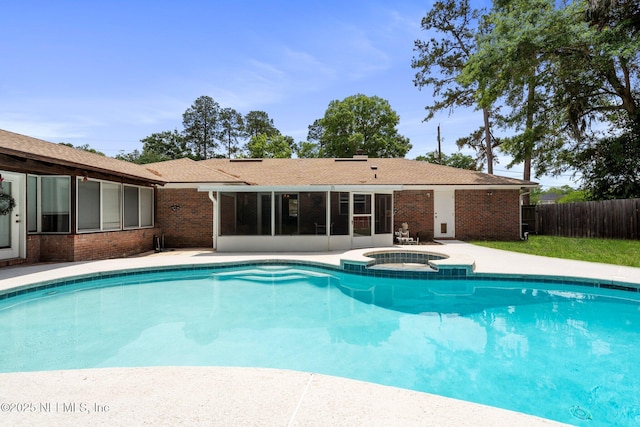 view of swimming pool featuring a patio, a pool with connected hot tub, fence, and a sunroom