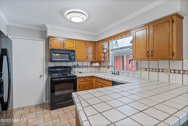 kitchen featuring a sink, tile counters, a peninsula, decorative backsplash, and black appliances