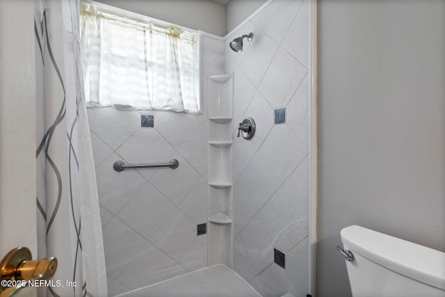 bathroom featuring a tile shower and toilet