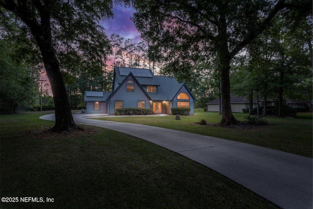 view of front of home featuring roof mounted solar panels, concrete driveway, and a front yard