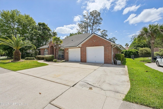 single story home featuring brick siding, a front lawn, an attached garage, and driveway