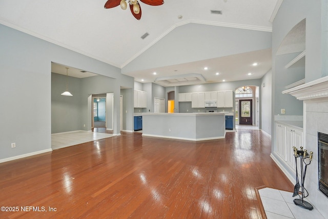 unfurnished living room with a ceiling fan, visible vents, crown molding, a fireplace, and light wood-style flooring