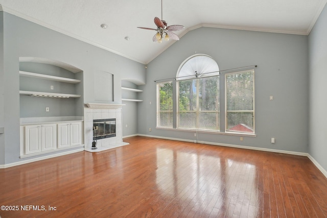 unfurnished living room featuring ceiling fan, a fireplace, built in shelves, wood finished floors, and baseboards