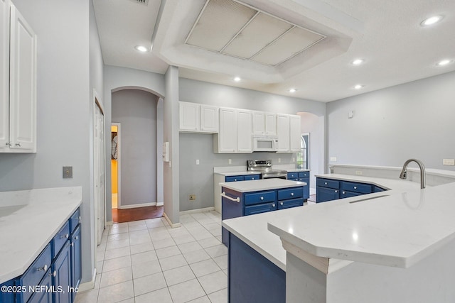 kitchen with stainless steel electric stove, arched walkways, blue cabinetry, and a spacious island