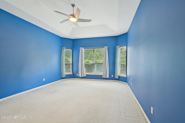 empty room featuring carpet floors, a ceiling fan, a textured ceiling, and a tray ceiling