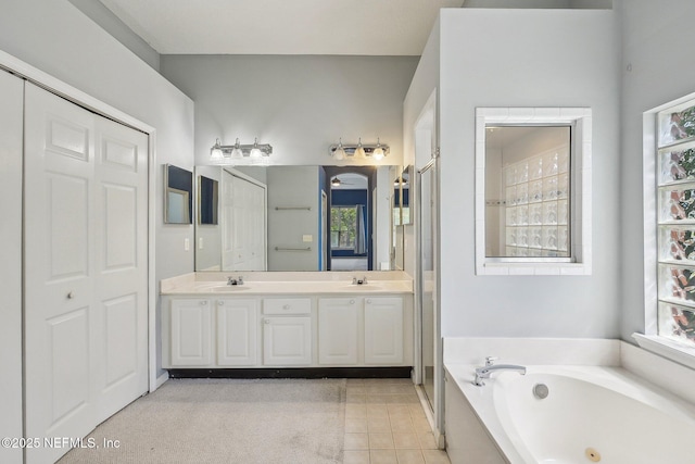bathroom with double vanity, tile patterned floors, a sink, and a whirlpool tub