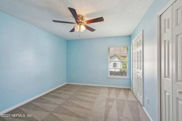 unfurnished bedroom with a closet, a textured ceiling, carpet, and baseboards