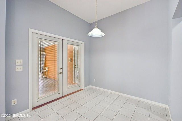 empty room with baseboards, light tile patterned flooring, and french doors