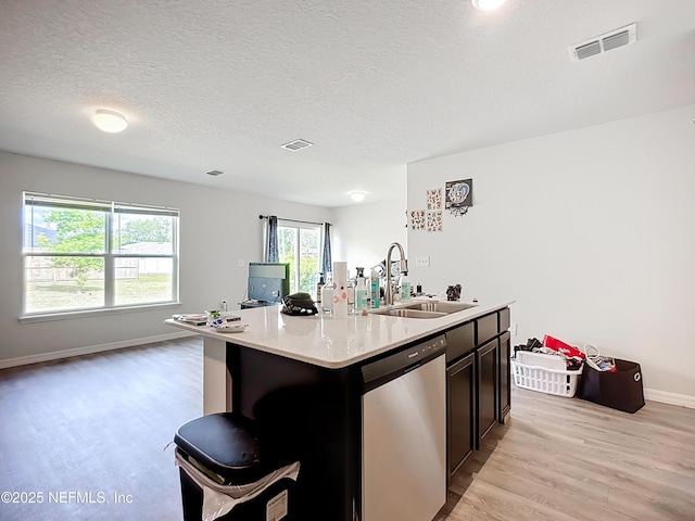 kitchen featuring a kitchen island with sink, visible vents, stainless steel dishwasher, a sink, and light wood-style floors