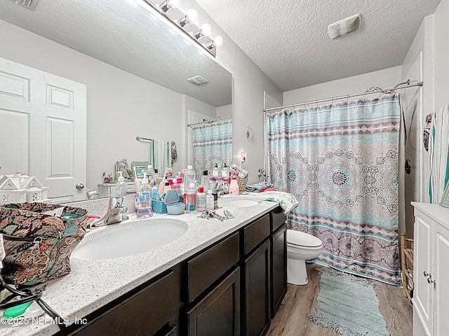 bathroom with double vanity, wood finished floors, toilet, a shower with shower curtain, and a sink