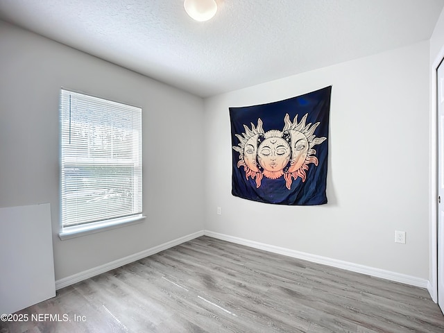 unfurnished room with baseboards, a textured ceiling, and wood finished floors