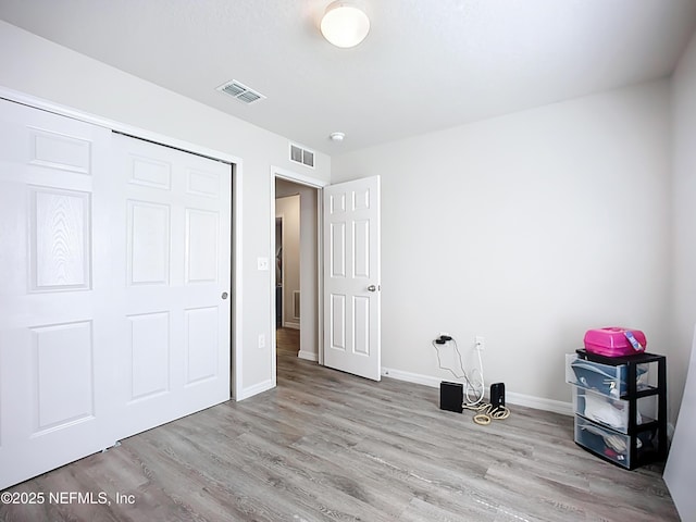 unfurnished bedroom with baseboards, visible vents, and wood finished floors