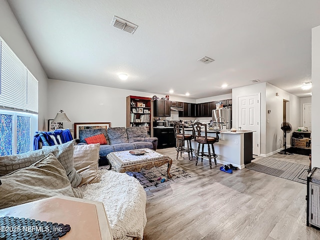 living area with light wood-style floors, baseboards, recessed lighting, and visible vents