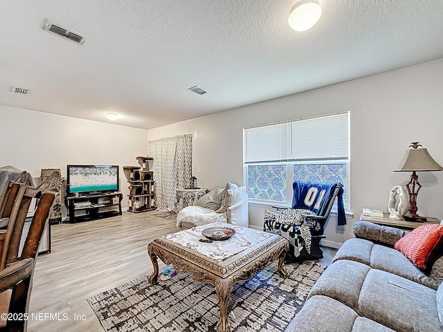 living area featuring visible vents, a textured ceiling, and light wood-style floors