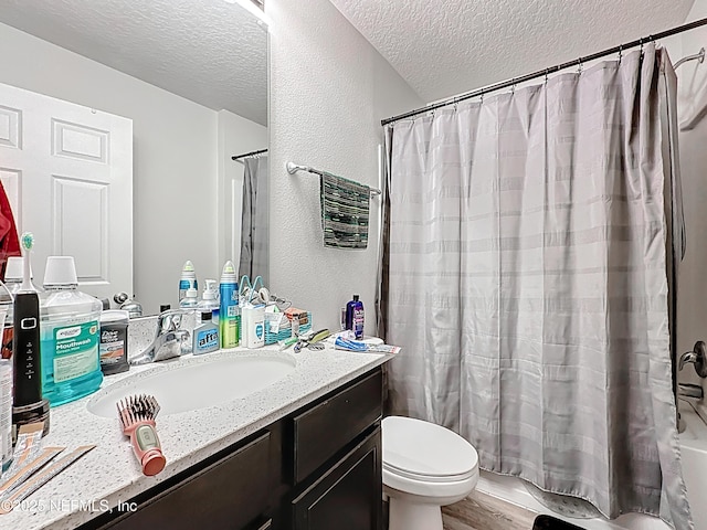 bathroom with vanity, wood finished floors, toilet, shower / bathtub combination with curtain, and a textured ceiling