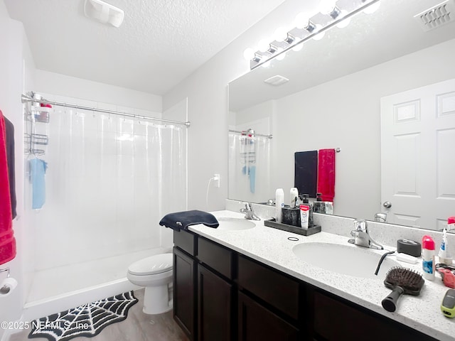 full bathroom featuring a shower with shower curtain, toilet, visible vents, and a sink