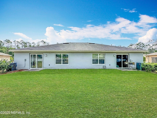 back of property with a lawn, central AC, and stucco siding