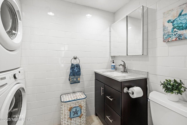 3365 N Ocean Shore Blvd, Flagler Beach, FL 32136 - bathroom featuring toilet, tile walls, stacked washer / dryer, and vanity