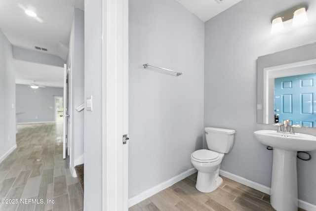 10318 Benson Lake Dr, Jacksonville, FL 32222 - half bathroom with wood finished floors, toilet, a sink, baseboards, and vaulted ceiling