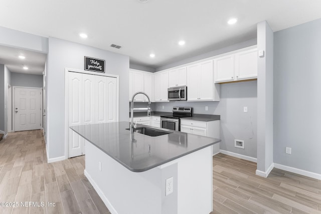 10318 Benson Lake Dr, Jacksonville, FL 32222 - kitchen with stainless steel appliances, a sink, dark countertops, light wood finished floors, and white cabinets