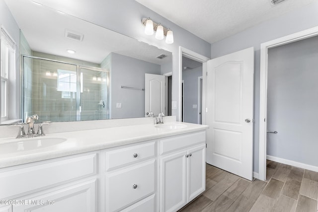 10318 Benson Lake Dr, Jacksonville, FL 32222 - full bath featuring a shower stall, double vanity, wood finished floors, baseboards, and a textured ceiling