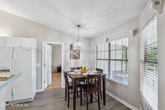 400 Harvest Bend Dr, Fleming Island, FL 32003 - dining room with healthy amount of natural light, wood finished floors, baseboards, a chandelier, and a textured ceiling