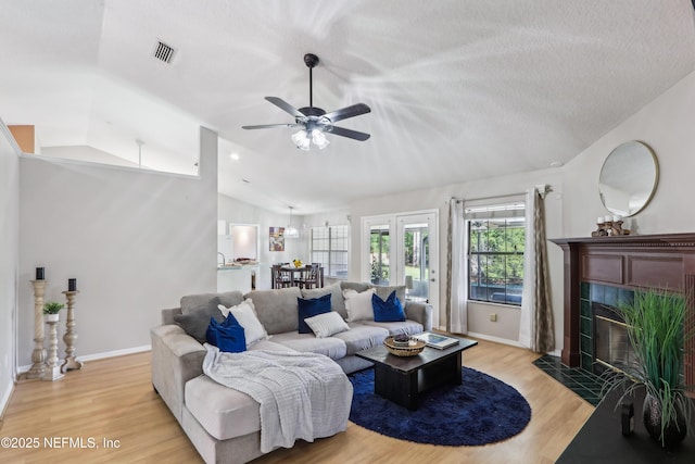 400 Harvest Bend Dr, Fleming Island, FL 32003 - living area with vaulted ceiling, a tiled fireplace, light wood-style flooring, ceiling fan, and baseboards
