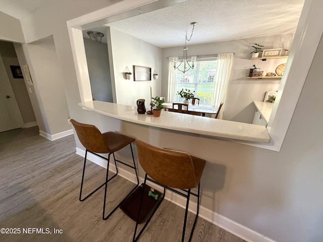 2599 Sandy Hollow Dr, Middleburg, FL 32068 - kitchen featuring wood finished floors, a kitchen bar, a chandelier, hanging light fixtures, and a textured ceiling